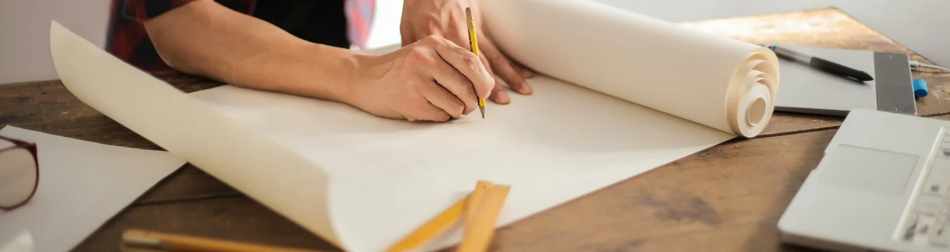 Person drawing with laptop on table